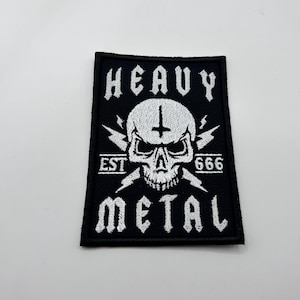 May include: Black rectangular patch with white embroidered text and a skull graphic. The patch reads "HEAVY METAL" with "EST 666" and a skull with a cross and lightning bolts.