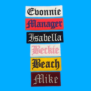 May include: Six embroidered iron-on patches with names in old English font. The names are Evonnie, Manager, Isabella, Beckie, Beach, and Mike. The patches are in various colors, including white, red, black, pink, yellow, and maroon.