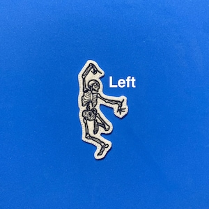 May include: White embroidered patch of a skeleton dancing with the word "Left" in white text.