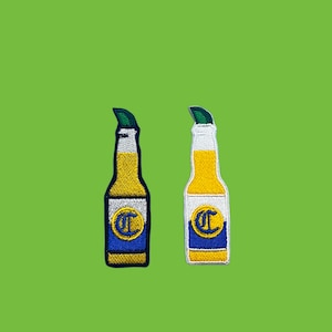 May include: Two embroidered iron-on patches of Corona beer bottles. The bottles are yellow with a blue and white label that says "Corona Extra".