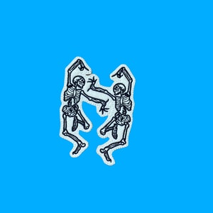 May include: Two white embroidered skeletons dancing against a bright blue background.