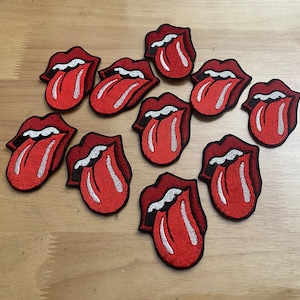 May include: Ten red and white embroidered iron-on patches of a tongue sticking out, each with a black outline.