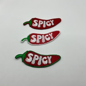 May include: Three embroidered patches in the shape of red chili peppers with the word "SPICY" in white. Each pepper has a green stem. The patches are on a white background.