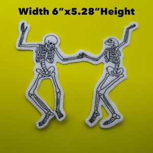 May include: White and black embroidered patch featuring two dancing skeletons holding hands. The patch is 6 inches wide and 5.28 inches high. The skeletons are outlined in black with white fill and are on a yellow background.