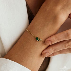 May include: A gold chain bracelet with green and yellow gemstone accents.