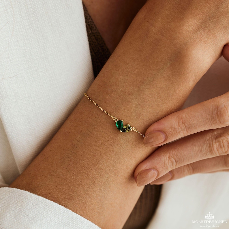 May include: A gold chain bracelet with green and yellow gemstone accents.