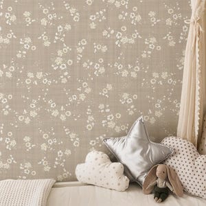 May include: A bedroom scene with a beige floral wallpaper backdrop. A canopy bed is draped with cream-colored fabric. Decorative pillows in various shapes and patterns, including a star and cloud, are arranged on the bed.