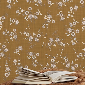 May include: Mustard-colored floral wallpaper with a repeating pattern of small white flowers and gray leaves. A brown knitted throw blanket with fringe is draped over a gray bed. An open book rests on the blanket.