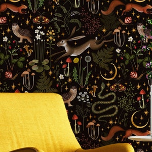 May include: A yellow armchair sits in front of a wall covered in a dark wallpaper with a whimsical forest design. The wallpaper features illustrations of owls, squirrels, snakes, mushrooms, and a running hare, with crescent moons and stars.