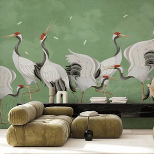 以下が含まれることがあります： 赤い頭と黒い翼の先を持つ白い鶴の群れが描かれた緑色の壁画。鶴はダイナミックなポーズをとっており、一部は飛んでいて、一部は地面に立っています。この壁画は美しくユニークな芸術作品であり、どんな部屋にもエレガントな雰囲気を加えるでしょう。