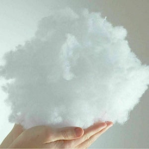 May include: A large, fluffy, white cloud-like ball of fibrefill held in a person's hands.