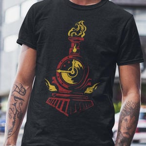 May include: Black t-shirt with a red and yellow train graphic. The design includes a clock face and flames. The t-shirt is made of a soft material and is suitable for casual wear.