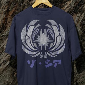 May include: A navy blue t-shirt with a white and purple graphic of a stylized creature with the text "ソ・ラ" printed below.