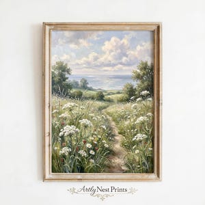 Puede incluir: Pintura de paisaje enmarcada que representa un camino a través de un campo de flores silvestres que conduce a una masa de agua bajo un cielo nublado. La obra de arte presenta una paleta de verdes, blancos, azules y marrones, con el texto "Artly Nest Prints" en la parte inferior.