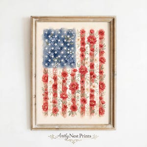 May include: A framed watercolour print depicting the American flag. The blue section features white stars and blue flowers, while red stripes are replaced with red roses and white flowers. The print is in a wooden frame, with the text "Artly Nest Prints".