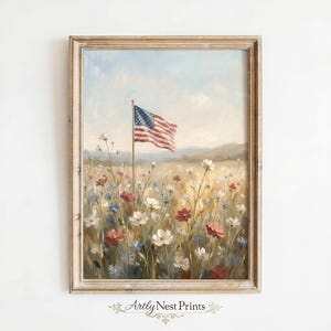 May include: A framed painting depicts an American flag waving in a field of wildflowers. The artwork features a color palette of red, white, blue, and yellow, with a soft, impressionistic style. The painting is in a light-colored wooden frame.
