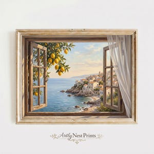 May include: A framed wall art print depicting an open wooden window looking out onto a coastal Mediterranean village by the sea. A lemon tree branch with yellow fruit hangs in the foreground, and a sheer white curtain blows in the breeze.