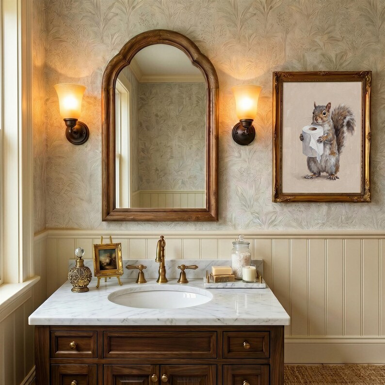 May include: Bathroom interior with a dark wood vanity, marble countertop, and a white oval sink. A large arched mirror and a framed squirrel artwork hang on the wall. Two sconces provide warm lighting. The room has a classic, elegant style.