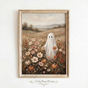 May include: A framed wall art print featuring an oil painting of a white ghost standing in a field of wildflowers and pumpkins. The landscape shows rolling hills under a soft sky. The text Arty Nest Prints is visible at the bottom centre.