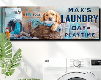 May include: A white laundry room with a white washing machine and a framed print above it. The print features a golden retriever dog in a basket of laundry with the text "Max's Laundry Day = Playtime" and "Est. 2021".