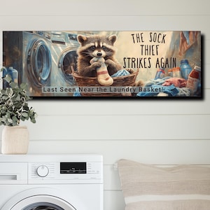 May include: A raccoon wearing a blue bandana is holding a sock in its paws. The raccoon is sitting in a laundry basket in front of a washing machine. The text "The Sock Thief Strikes Again! Last Seen Near the Laundry Basket!" is printed on the image.