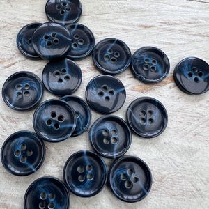 Könnte beinhalten: Eine Sammlung von 15 Knöpfen mit vier Löchern, die in einem blauen und weißen Wirbelmuster gehalten sind.