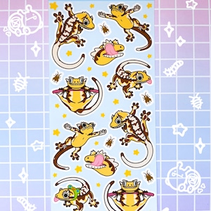May include: A sheet of stickers featuring a variety of cute crested gecko illustrations in yellow, brown, and white. The stickers are on a light blue background with yellow stars and brown bugs. The text "crested bestie" is at the top of the sheet.