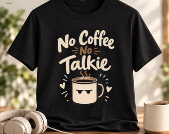 May include: A black short-sleeve t-shirt featuring the text No Coffee No Talkie in cream and brown lettering. Below the text is a graphic of a cream-colored coffee mug with a grumpy face, steam, and small hearts on a black background.
