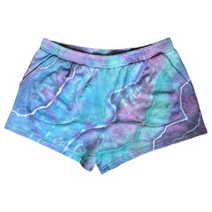 May include: Tie-dye shorts in shades of blue, purple, and green. The shorts have a drawstring waistband and side pockets.