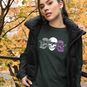 May include: A dark green long-sleeved shirt with a graphic of three skulls and the text "more than skin deep".
