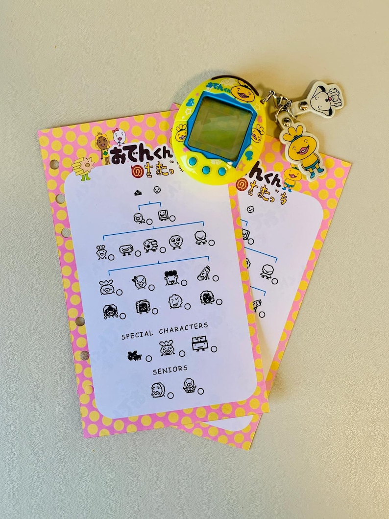May include: A yellow handheld digital pet toy with a screen, a keychain with cartoon characters, and two pink and yellow polka dot cards with Japanese text and character illustrations. The cards have a diagram of characters.