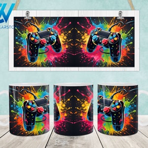 May include: Three white ceramic mugs with a black and colorful design featuring a video game controller with colorful paint splatters. The mugs are perfect for gamers and video game enthusiasts.