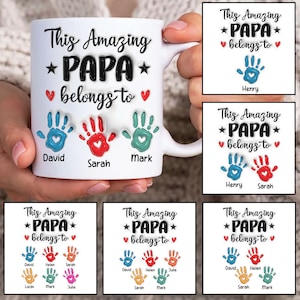 May include: White ceramic mug with a black and white design that says "This Amazing *PAPA* belongs to" with handprints and names below.