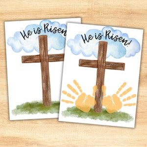May include: Two printable cards with a watercolor illustration of a wooden cross and a cloud with the text "He is Risen!" The second card also has two handprints below the cross.