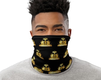 May include: A black neck gaiter with a repeating pattern of the gold coat of arms of Antigua and Barbuda. The coat of arms features a palm tree, a ship, and a shield.