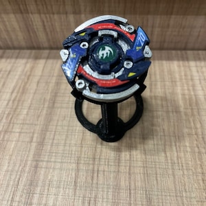 May include: A blue, red, and silver spinning top with a green dragon design on the center. The top is on a black plastic stand.