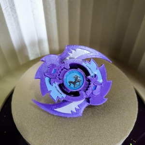 以下が含まれることがあります： 紫と白のベイブレードで、青と白の中央部分には馬のデザインが施されています。ベイブレードには「Lycanior」というラベルが貼られています。