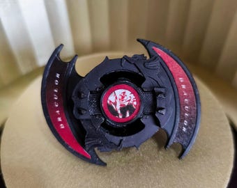 May include: Black and red plastic Beyblade with the word "DRACULOR" printed on the side. The Beyblade has a red and white design in the center.