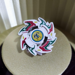Può includere: Beyblade di plastica bianca, rossa e verde con un design a forma di drago e le parole "DRAGOON D" sul lato.