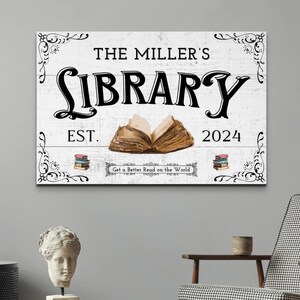 May include: White wooden sign with black text that reads "The Miller's Library Est. 2024 Get a Better Read on the World". The sign features a decorative border and an illustration of an open book.