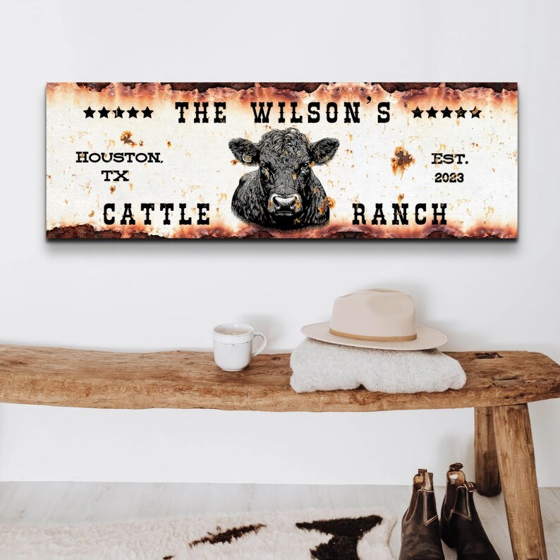 May include: A rusty metal sign with the text "THE WILSON'S CATTLE RANCH" and a black cow head illustration. The sign also includes the text "HOUSTON, TX" and "EST. 2023".