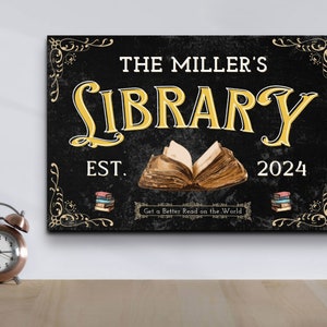 May include: Black and white sign with gold lettering that reads "The Miller's Library Est. 2024" with an open book illustration and the text "Get a Better Read on the World".