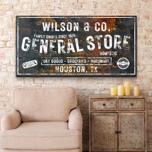 May include: A vintage-style sign for Wilson & Co. General Store, a family-owned business since 1978. The sign is made of distressed metal with a rusty brown and black color scheme. It features the text "Wilson & Co. General Store" in white lettering, along with the words "Family Owned Since 1978", "Domestic", "Dry Goods - Groceries - Hardware", "Locally Grown", and "Guarantee". The sign also includes the location "Houston, TX".