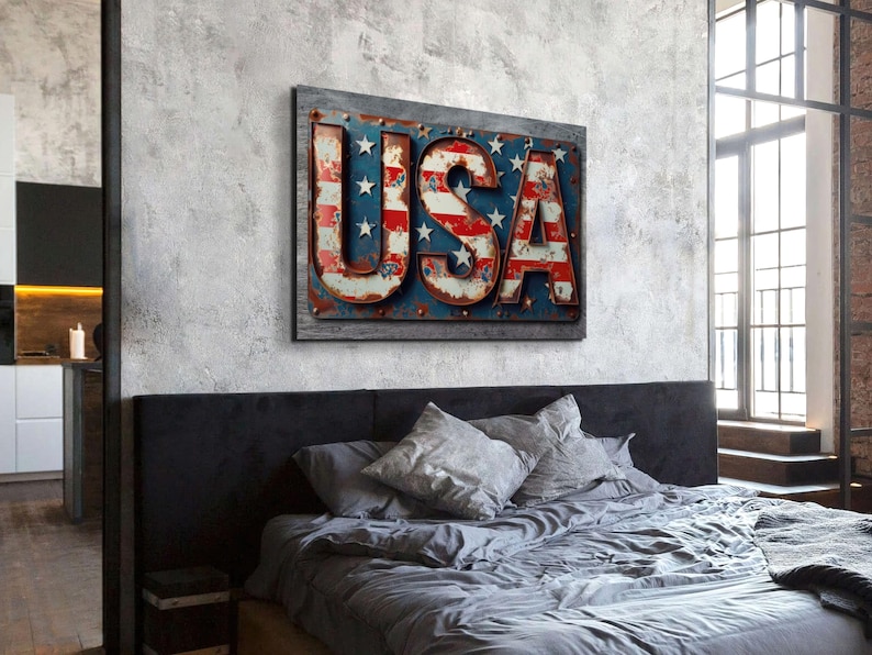 May include: A distressed metal sign with the word "USA" in large, bold letters. The letters are painted in red, white, and blue, resembling the American flag. The sign is hanging on a gray wall above a bed with gray bedding.