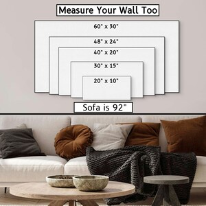 May include: A white sofa with brown throw pillows and a black throw blanket. The wall behind the sofa has a diagram showing different sizes of wall art with the text "Measure Your Wall Too" and "Sofa is 92" inches.