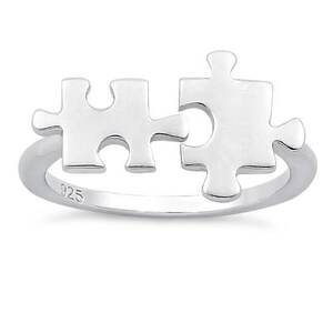 May include: Sterling silver ring featuring two interlocking puzzle pieces. The ring is marked with "925" on the band.