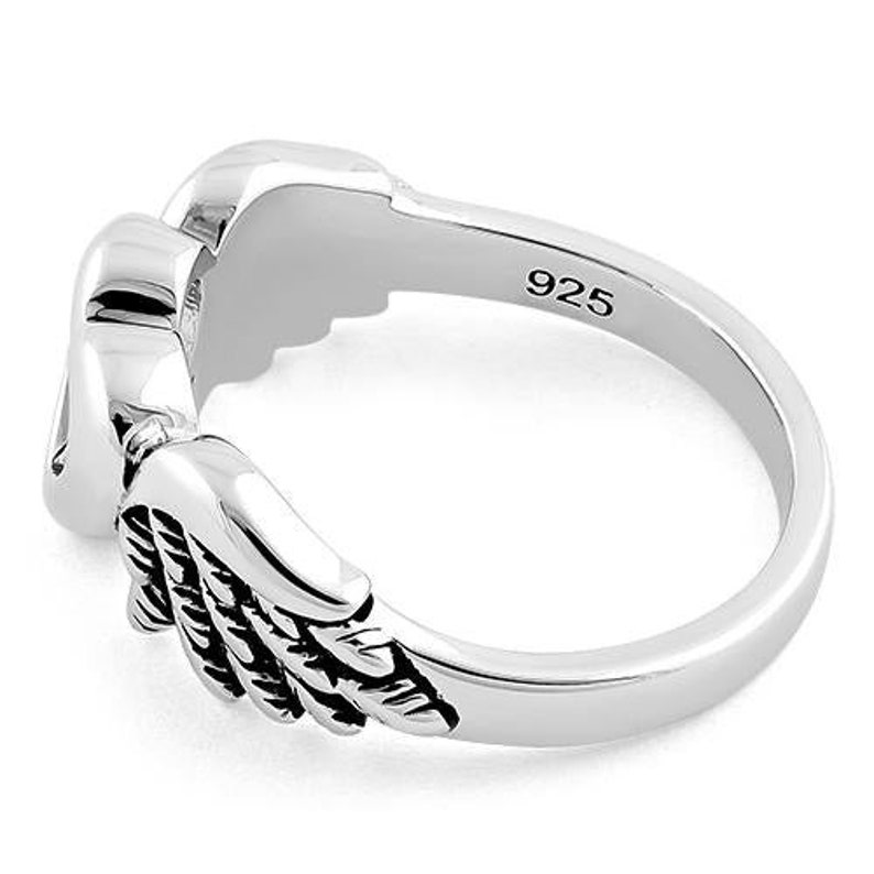 May include: A silver ring with a detailed wing design. The ring is made of polished metal and features a textured wing on each side of the ring. The inside of the ring is stamped with "925".