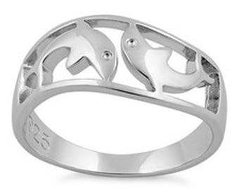 May include: A polished silver-tone ring featuring a cut-out design of two dolphins swimming in a circular formation. The band is smooth and includes a visible 925 stamp on the inner surface, indicating the metal composition of the jewelry piece.