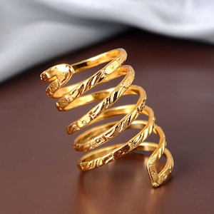 Puede incluir: Un anillo de espiral dorado con un diseño texturizado. El anillo está hecho de múltiples bandas que se retuercen juntas para crear una forma de espiral.