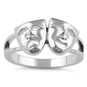 May include: A silver ring featuring two stylized faces, one smiling and one frowning, representing the masks of comedy and tragedy.